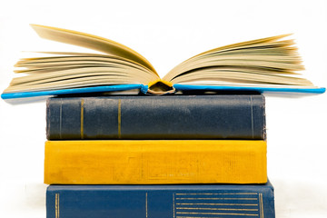 stack of books, a book on the top open pages, yellow, blue colors