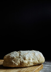 bread on a black background flour on the table