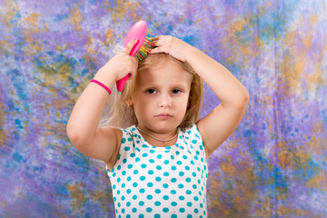 A child, a little girl combs her hair. Daily hair care and hygiene.