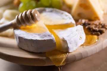 Cheese plate, honey pouring on camembert cheese