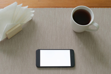 close-up hand holding phone white screen over work table