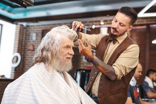 Be precise. Profile photo of cheerful old man that keeping smile on face while communicating with his barber