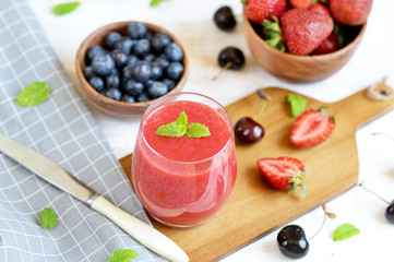 Delicious berries smoothie, strawberry, blueberry, cherry, wooden background, summer drink concept