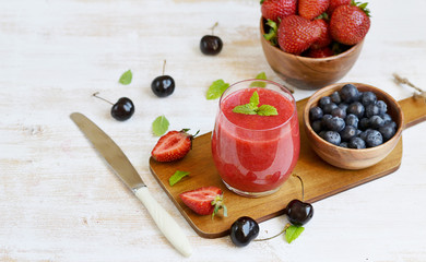 Delicious berries smoothie, strawberry, blueberry, cherry, wooden background, summer drink concept