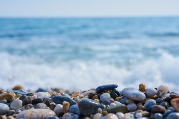 Stones on the beach with blured sea water and horizon on a background. 