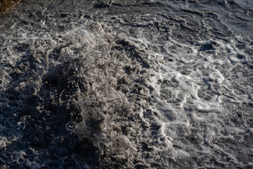 Water flows out of road sewage hatch. Drainage fountain of sewage.