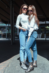 Fototapeta premium Two stylish girlfriends in fashionable clothes are walking on a summer day