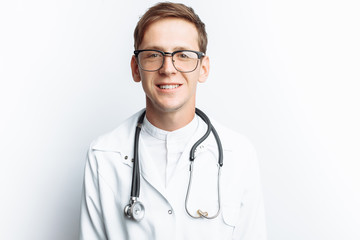 Fototapeta premium Portrait of a young doctor on a white background, Intern in the Studio, with a stethoscope on the neck