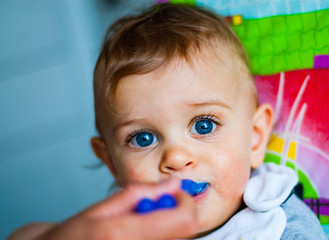 baby boy eating food with spoon at home