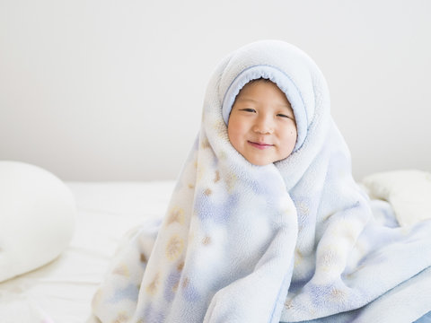 朝、布団にくるまって笑う男の子