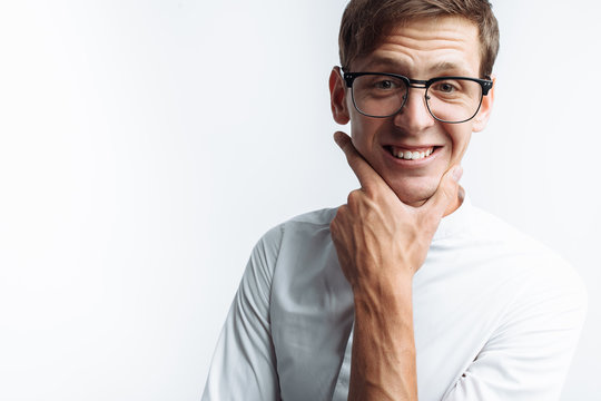 Portrait of young attractive guy in glasses depicting joy, in white shirt isolated on white background, for advertising, text insertion