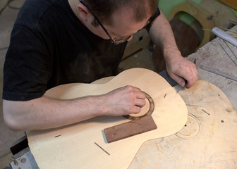 The guitar master installs  rosette in a classical guitar.