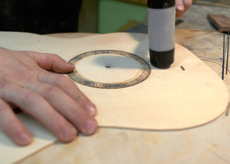 The guitar master installs  rosette in a classical guitar.