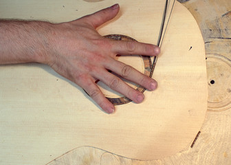The guitar master installs  rosette in a classical guitar.