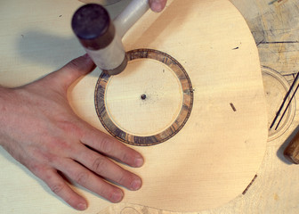 The guitar master installs  rosette in a classical guitar.