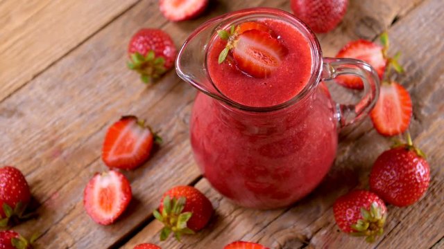 Fresh strawberry smoothie spinning on wooden table ready to drink. Healthy drinking concept. 4k