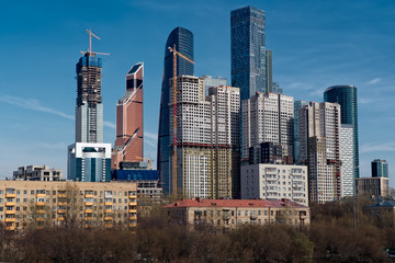 View on group of modern high-rise buildings with old last century buildings in the foreground. Blue sky. Moscow, Russia