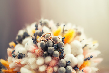 Wedding rings on bouquet of dry flowers.