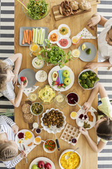 Top view of a wooden table with variety of fresh organic vegetables, fruit, salad and herbs. Kids eating delicious products during summer party. - obrazy, fototapety, plakaty