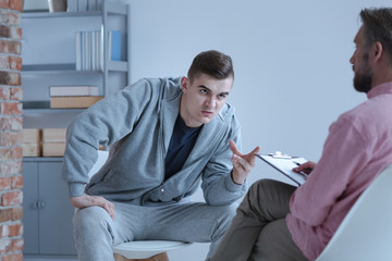 Aggressive young man and psychotherapist during therapy for rebellious people