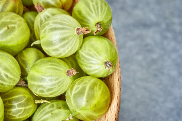 Close up picture of ripe gooseberries in a wooden bowl, shallow depth of field.