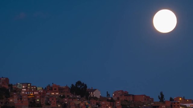 Moon rises over the city of La Paz. Bolivia. Timelapse with vertical panorama during twilight.