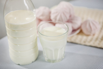 Glass and bottle of milk with pink sweets on the table