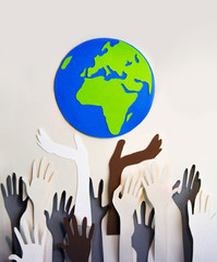 Humans hands raised up towards the Planet Earth sign. Togetherness, support and team building concept. 