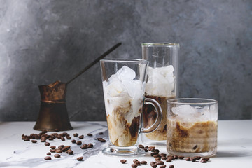 Iced coffee cocktail or frappe with ice cubes and cream served in three different glasses with...
