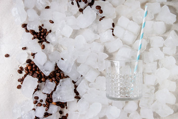 Coffe cocktail frappe making concept. cocktail glass with tube with roasted coffee beans over crushed ice cubes. Flat lay, space.