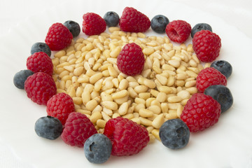 pine nuts and raspberries and blueberries on white background