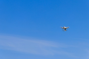 Drone with camera flying in blue sky