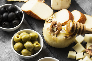 Snacks with wine - various types of cheeses, figs, nuts on a gray background