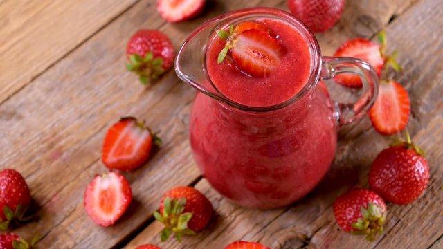 Fresh strawberry smoothie spinning on wooden table ready to drink. Healthy drinking concept. 4k