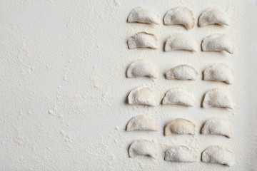 Raw handmade vareniki on table sprinkled with flour