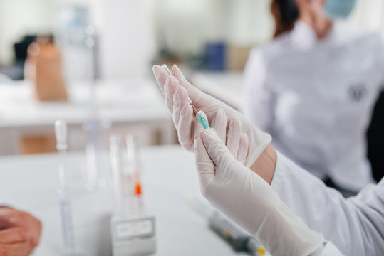 Female doctor holding suringe. Close-up.