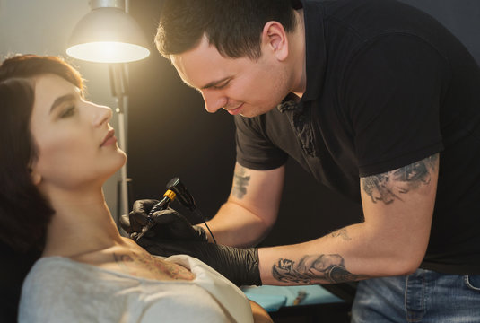 Tattoo artist working with needle on clients body