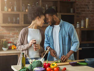 Fototapeta premium Loving african-american couple preparing dinner in kitchen