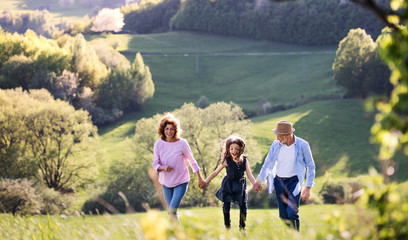 Senior couple with granddaughter on a walk outside in spring nature.