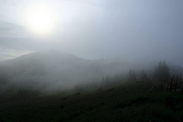 Mountain range with visible silhouettes through the morning colorful fog.