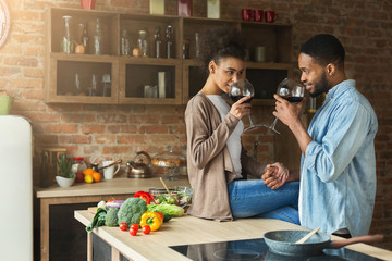 Loving african-american couple drinking wine in kitchen.
