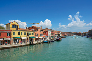 Fototapeta na wymiar View of buildings, in front of canal, with people and boats in Murano, a nice little town on top of islands near Venice. Located in the Veneto region, northern Italy