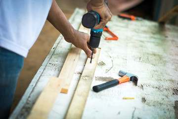 carpenter man using electric drill on worker table