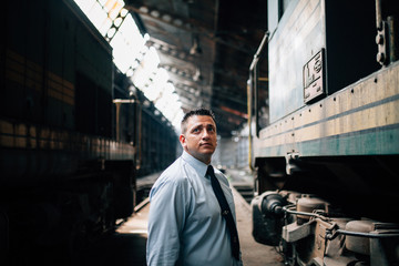 Wide portrait in the middle of two locomotives of a train driver with tie