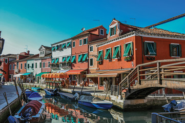 Fototapeta na wymiar View of colorful buildings, bridge and people in front of a canal at Burano, a gracious little town full of canals, near Venice. In the Veneto region, northern Italy