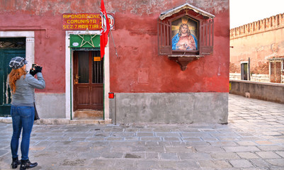 old building facade with entance in local communist party seat and immage of Jesus on the wall sacred and profane