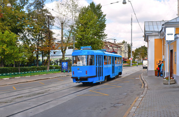 Naklejka premium Old blue tram on street of Moscow with blue cloudy sky and historical old buildings in background 
