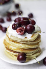 pancakes with yogurt and cherry on a white background.