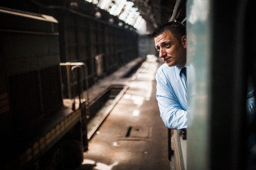 Young train driver looking outside from the cab of a diesel locomotive in the depot