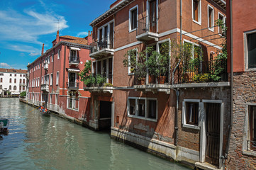 Fototapeta na wymiar View of buildings in front of the canal with gondola in the background, at the city center of Venice, the historic and amazing marine city. Veneto region, northern Italy
